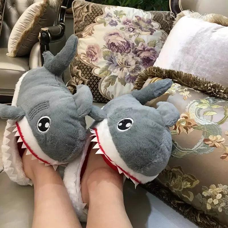 A woman wearing a pair of Silly Sausage shark-themed Animal Slippers while enjoying cozy comfort on a couch.